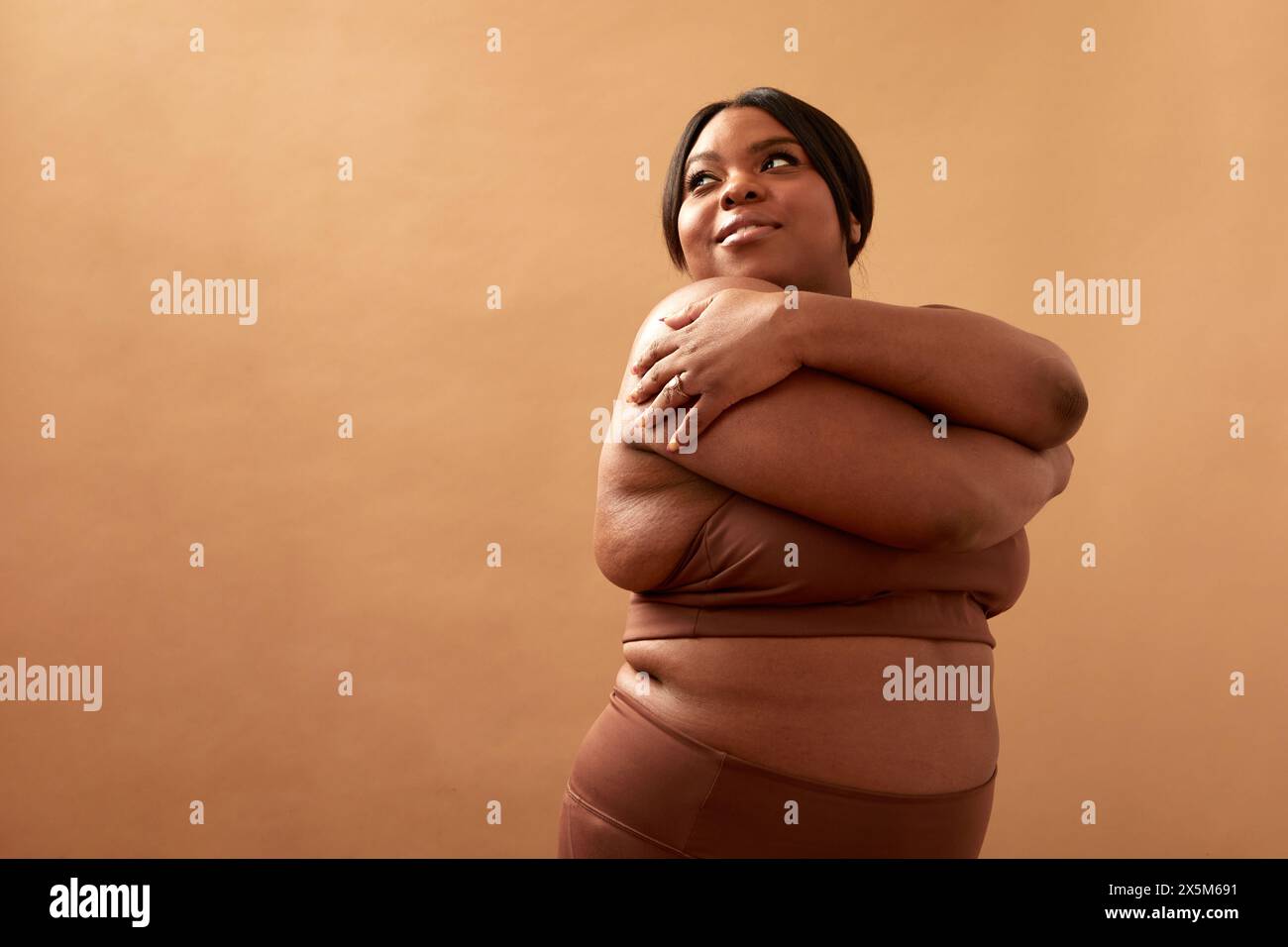 Photo studio d'une femme grande taille dans des vêtements de sport étirant les bras Banque D'Images