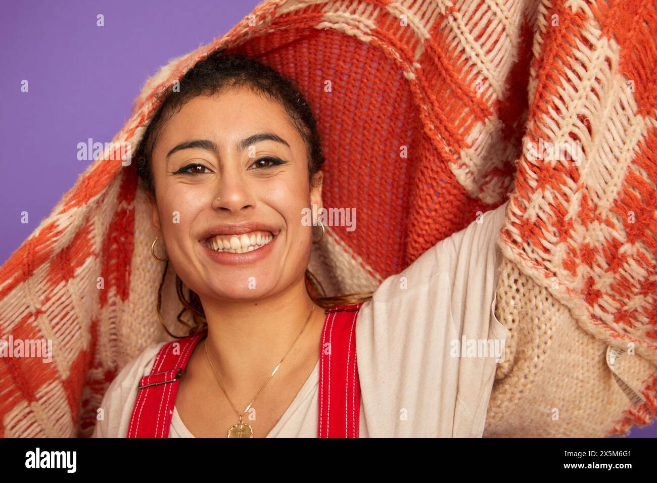 Portrait de studio de femme souriante tenant un pull au-dessus de la tête Banque D'Images