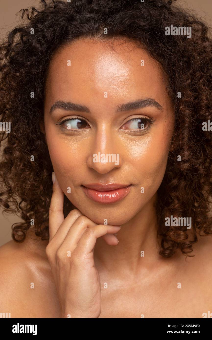 Photo de studio d'une femme souriante avec les cheveux bouclés regardant loin Banque D'Images