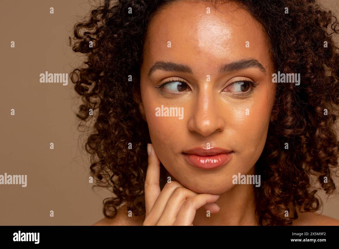 Photo de studio d'une femme souriante avec les cheveux bouclés regardant loin Banque D'Images
