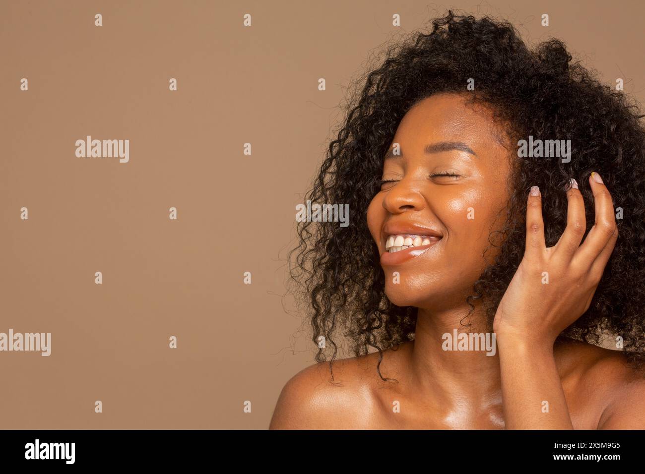 Photo de studio d'une femme souriante avec des cheveux bouclés Banque D'Images