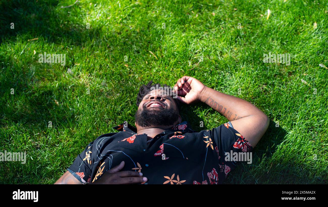 Homme souriant allongé sur l'herbe Banque D'Images