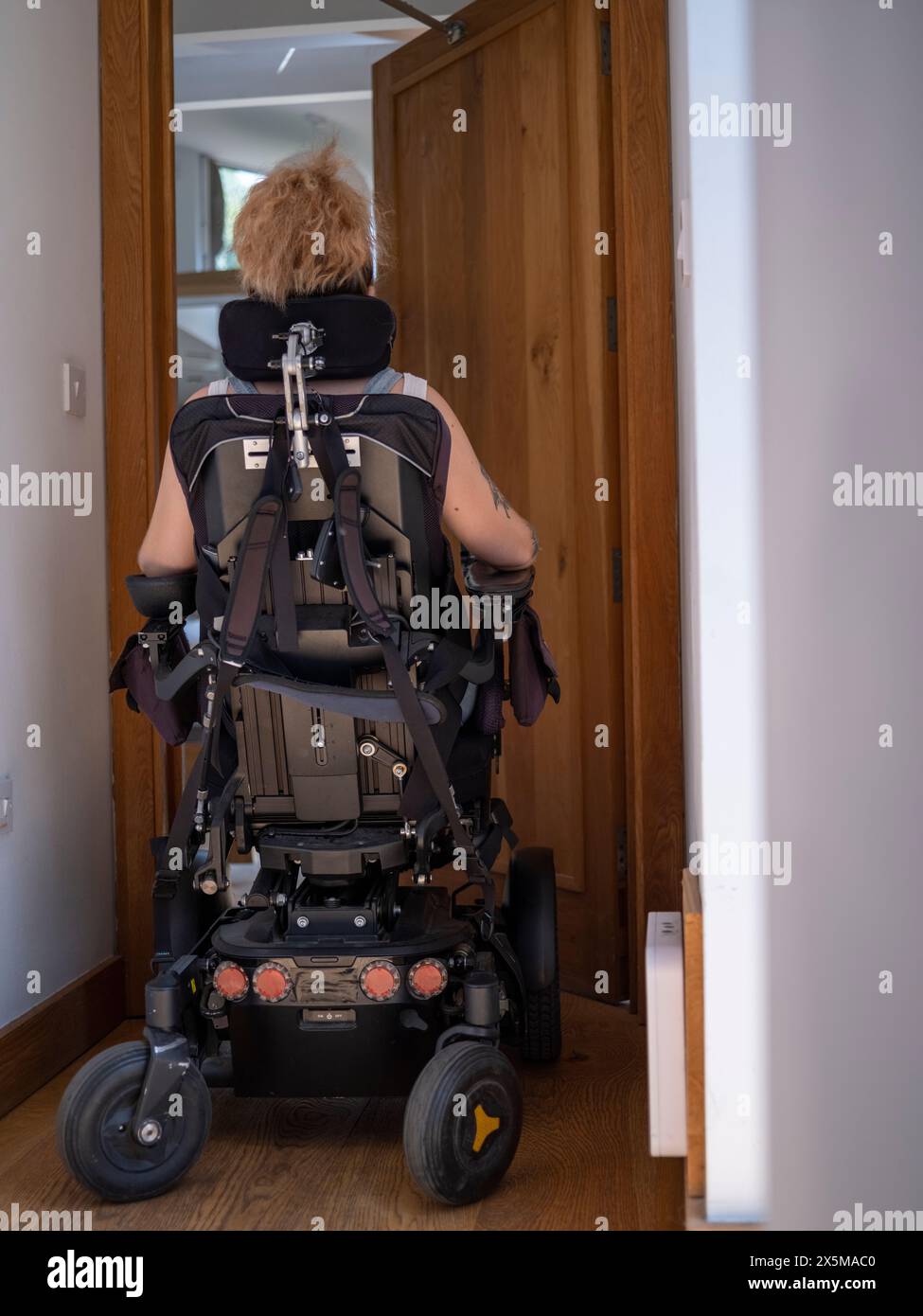 Femme en fauteuil roulant électrique passant par des portes automatiques Banque D'Images