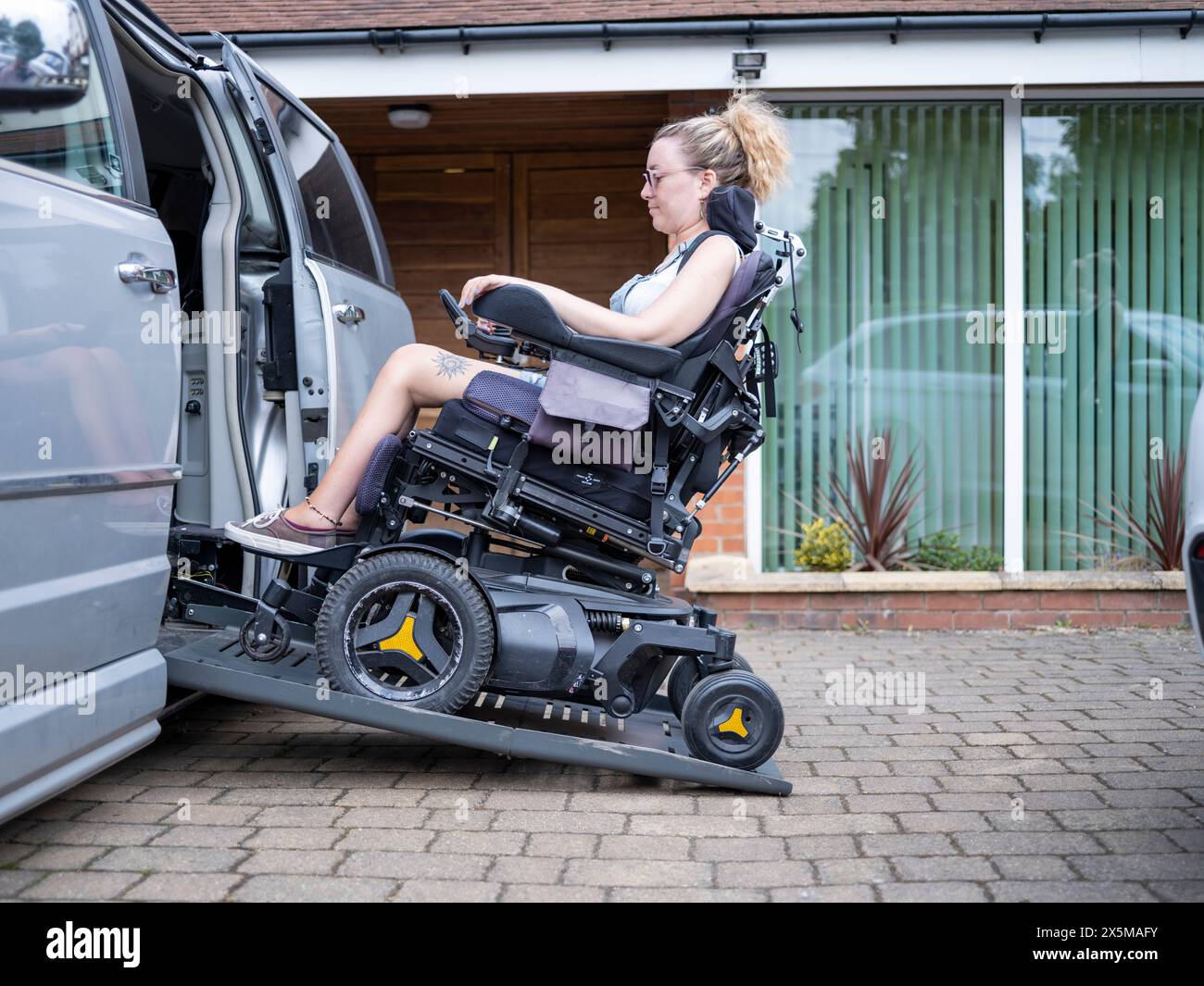 Femme en fauteuil roulant électrique entrant dans la camionnette Banque D'Images