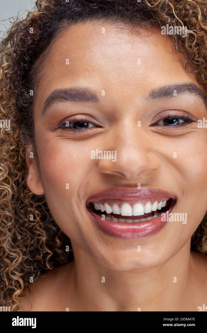 Gros plan d'une femme souriante avec des cheveux bouclés Banque D'Images