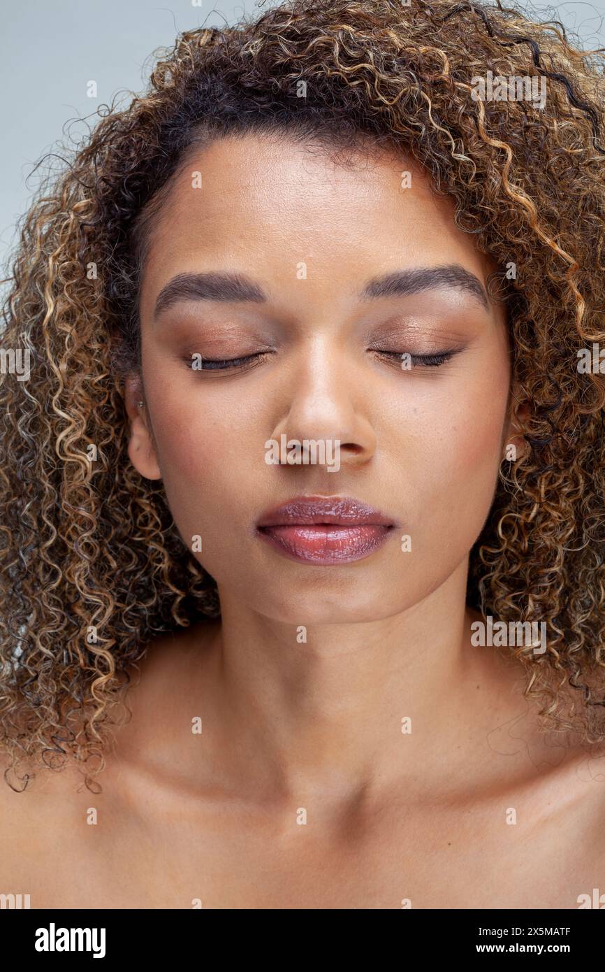 Portrait studio de femme avec les cheveux bouclés et les yeux fermés Banque D'Images