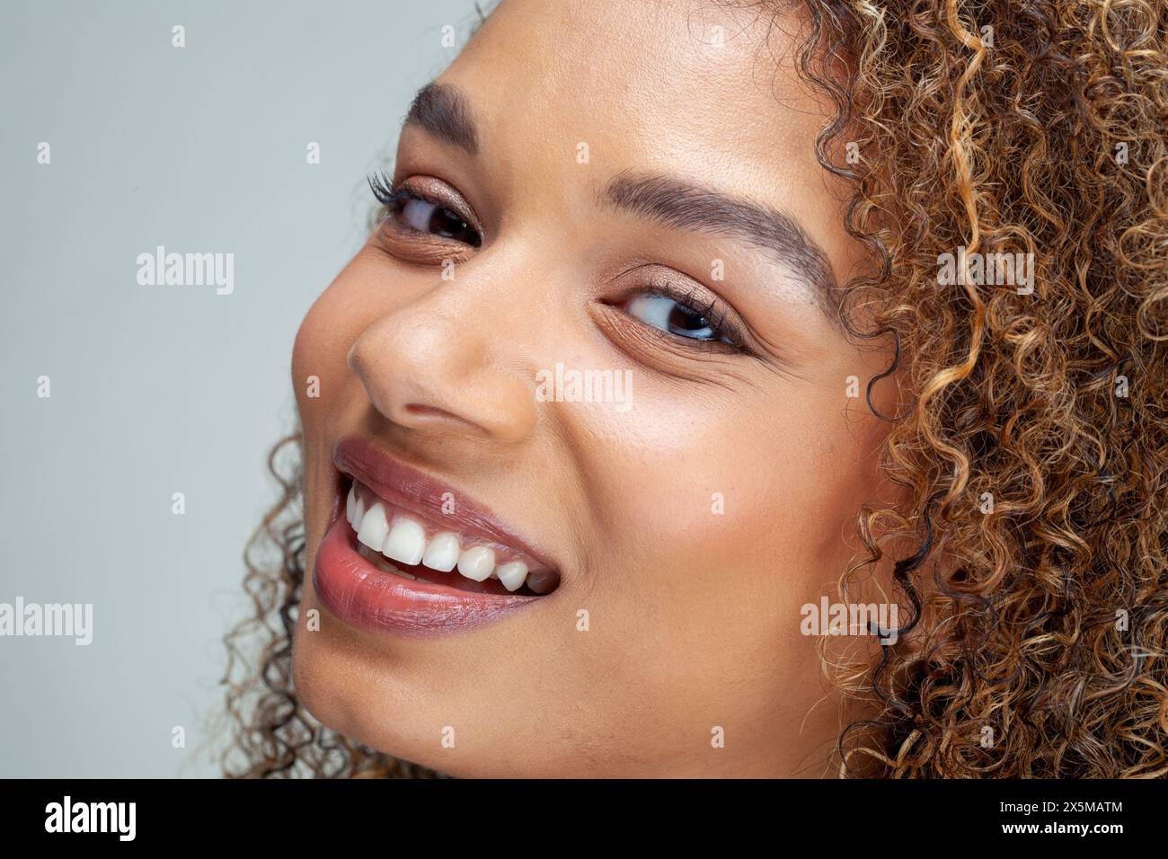 Gros plan d'une femme souriante avec des cheveux bouclés Banque D'Images