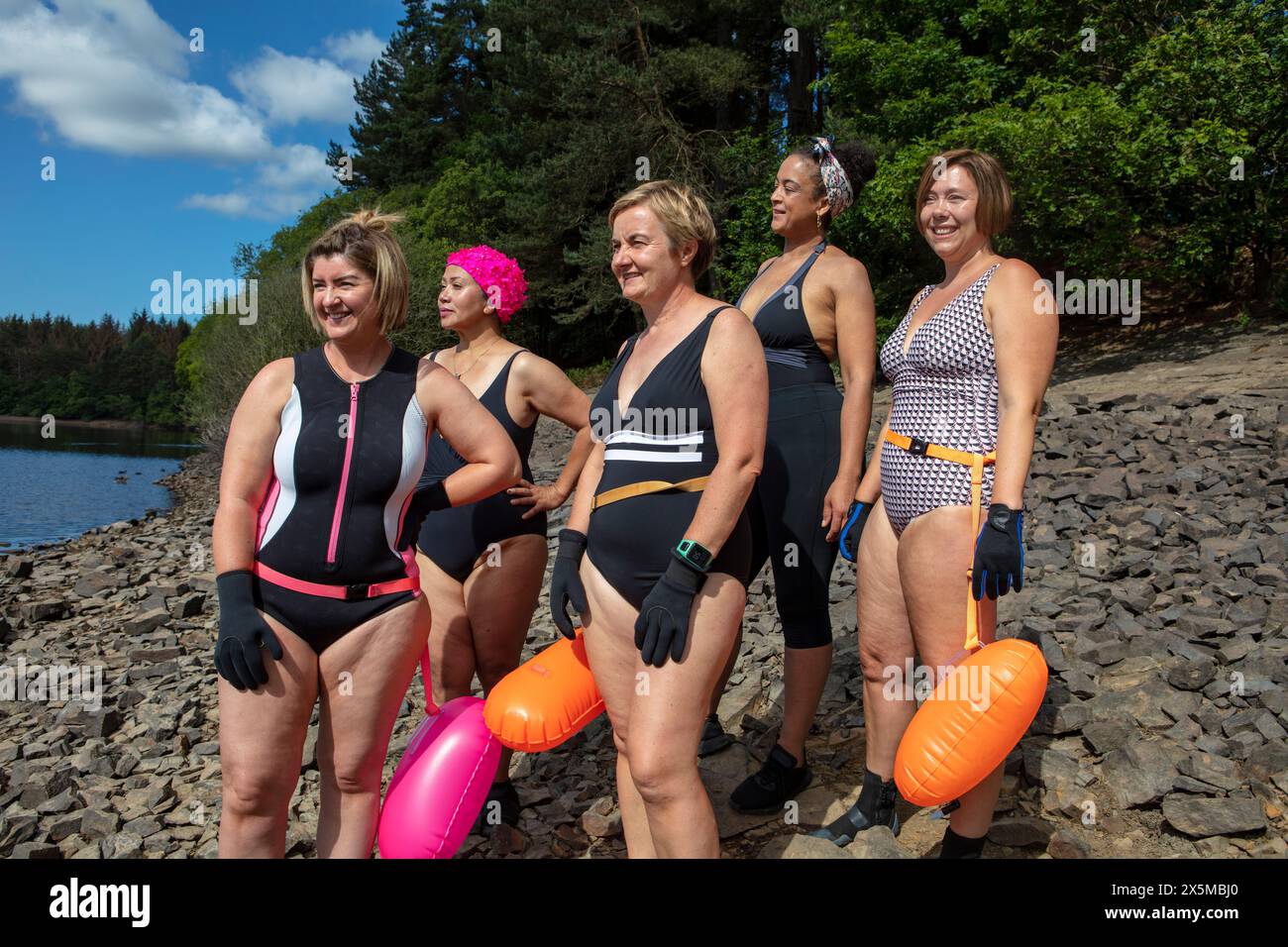 Amies féminines en maillots de bain debout sur le bord du lac rocheux, Yorkshire, Royaume-Uni Banque D'Images