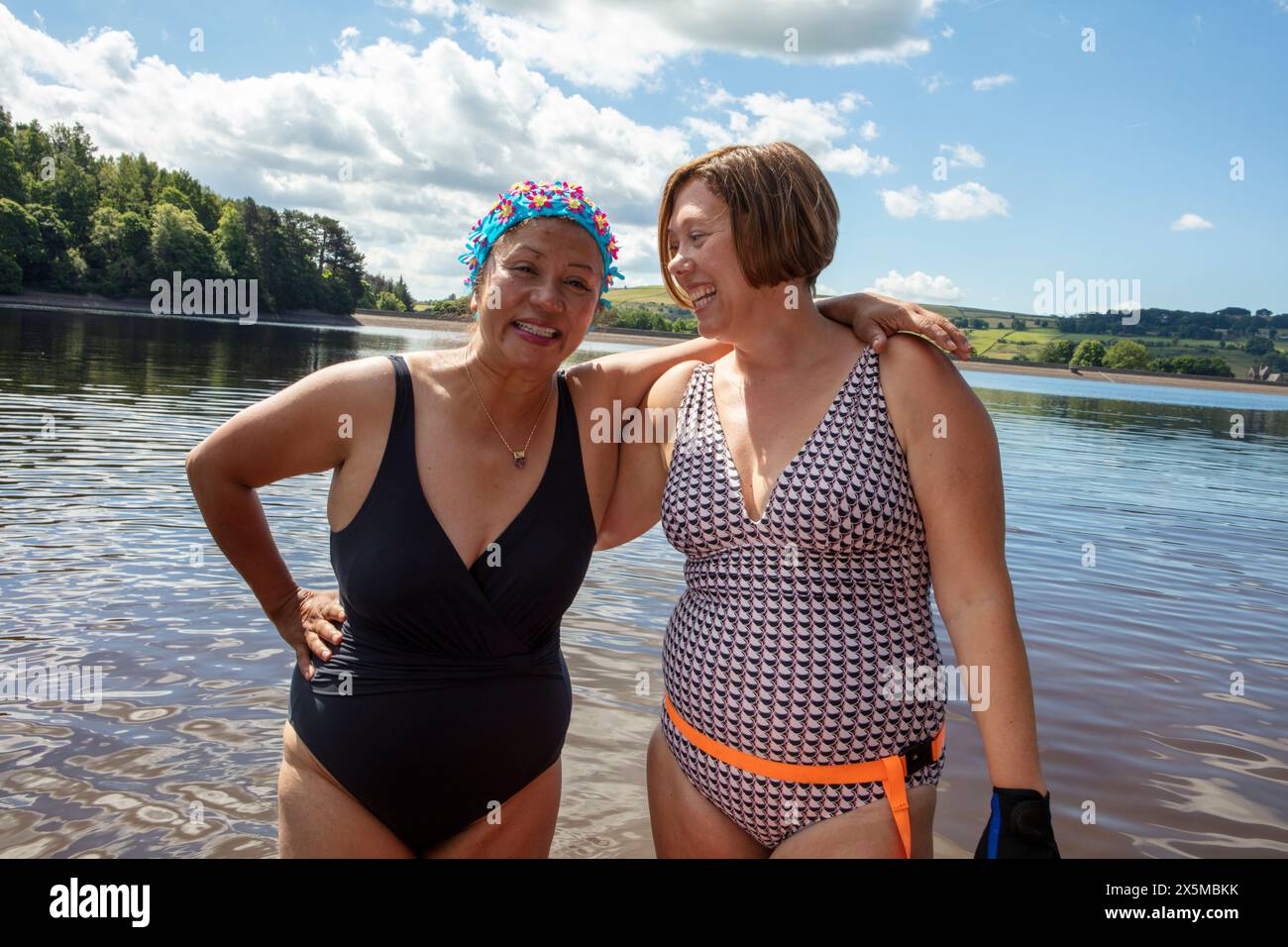 Amies féminines souriantes debout dans le lac, Yorkshire, Royaume-Uni Banque D'Images