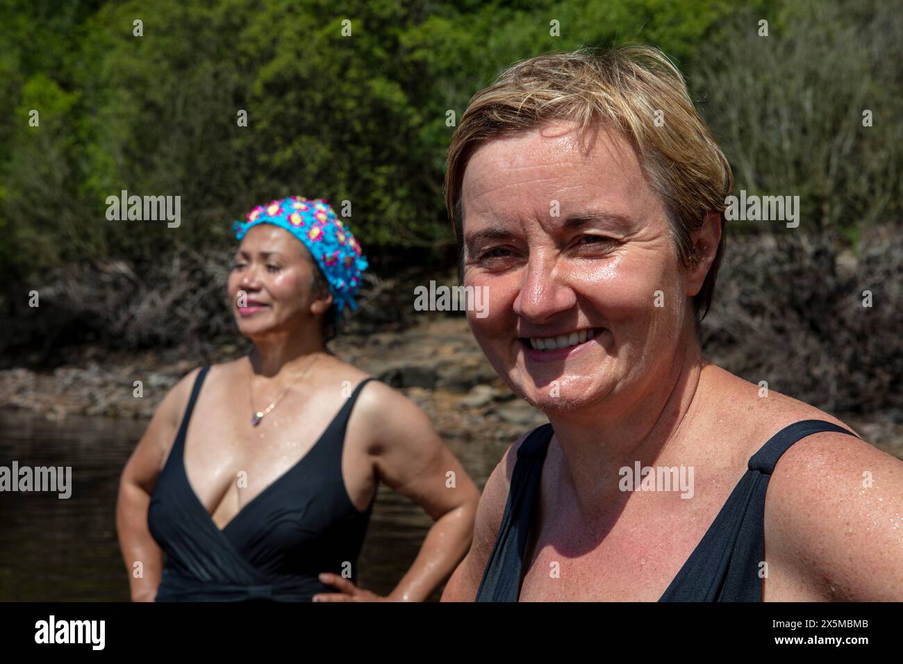 Amies féminines souriantes debout dans le lac, Yorkshire, Royaume-Uni Banque D'Images