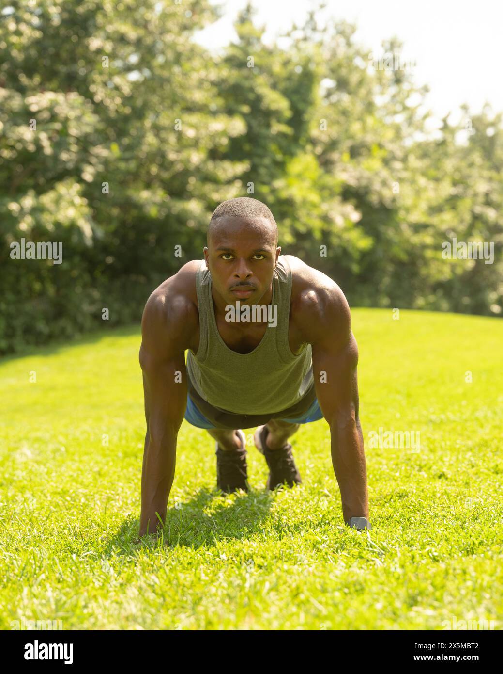 Homme athlétique faisant des pompes sur la pelouse dans le parc Banque D'Images