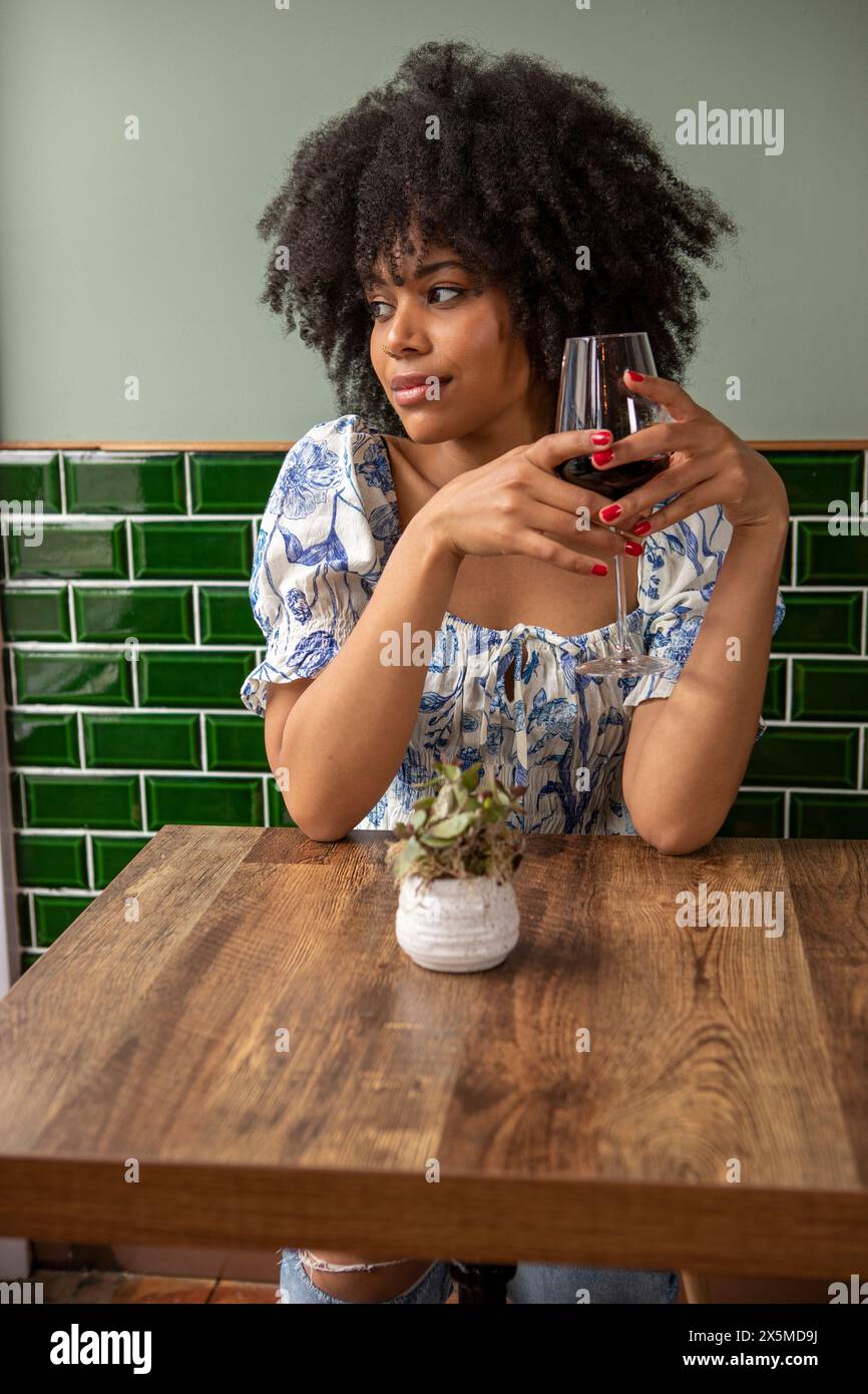 Royaume-Uni, Londres, Pensive femme avec un verre de vin rouge à la table de café Banque D'Images