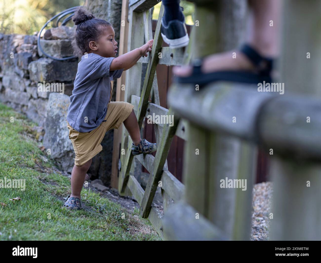 Garçon (2-3) grimpant à la clôture Banque D'Images