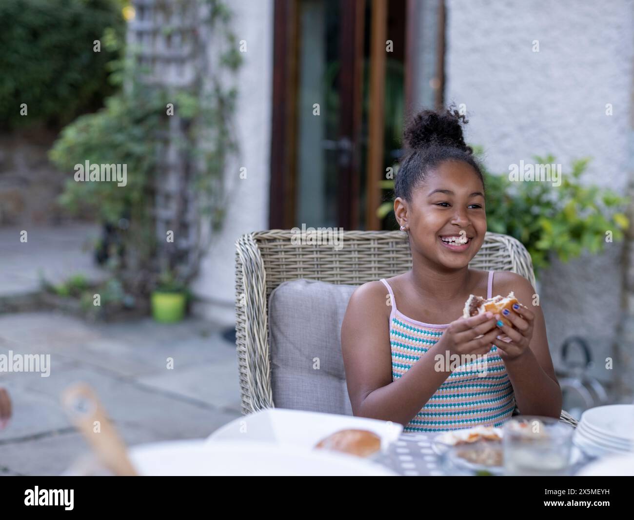 Fille souriante (8-9) mangeant un hamburger Banque D'Images