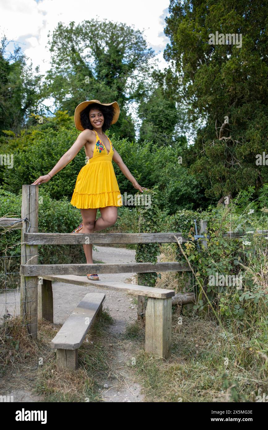 Jeune femme portant une robe jaune grimpant à la clôture Banque D'Images