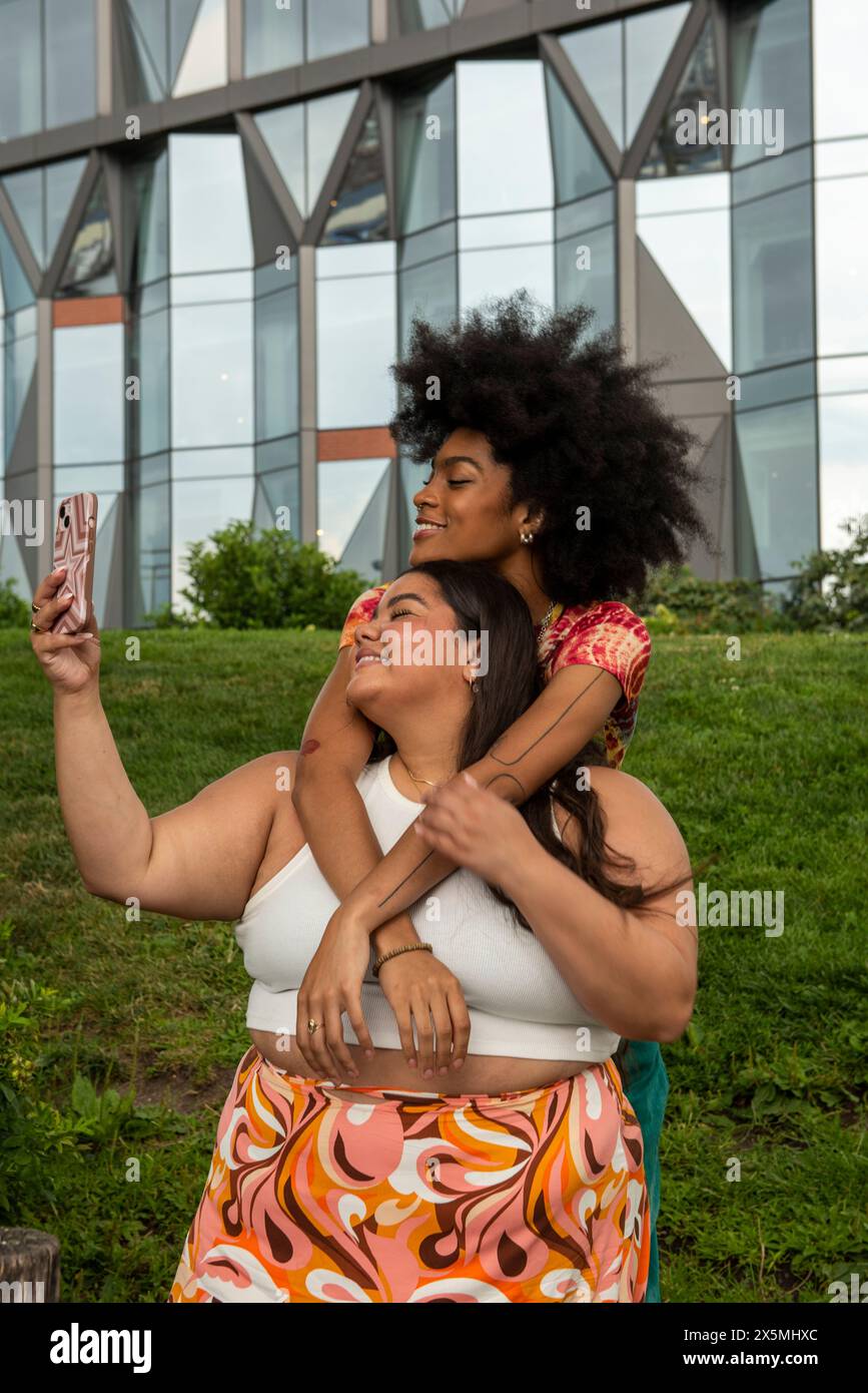 Deux jeunes femmes prenant selfie en milieu urbain Banque D'Images