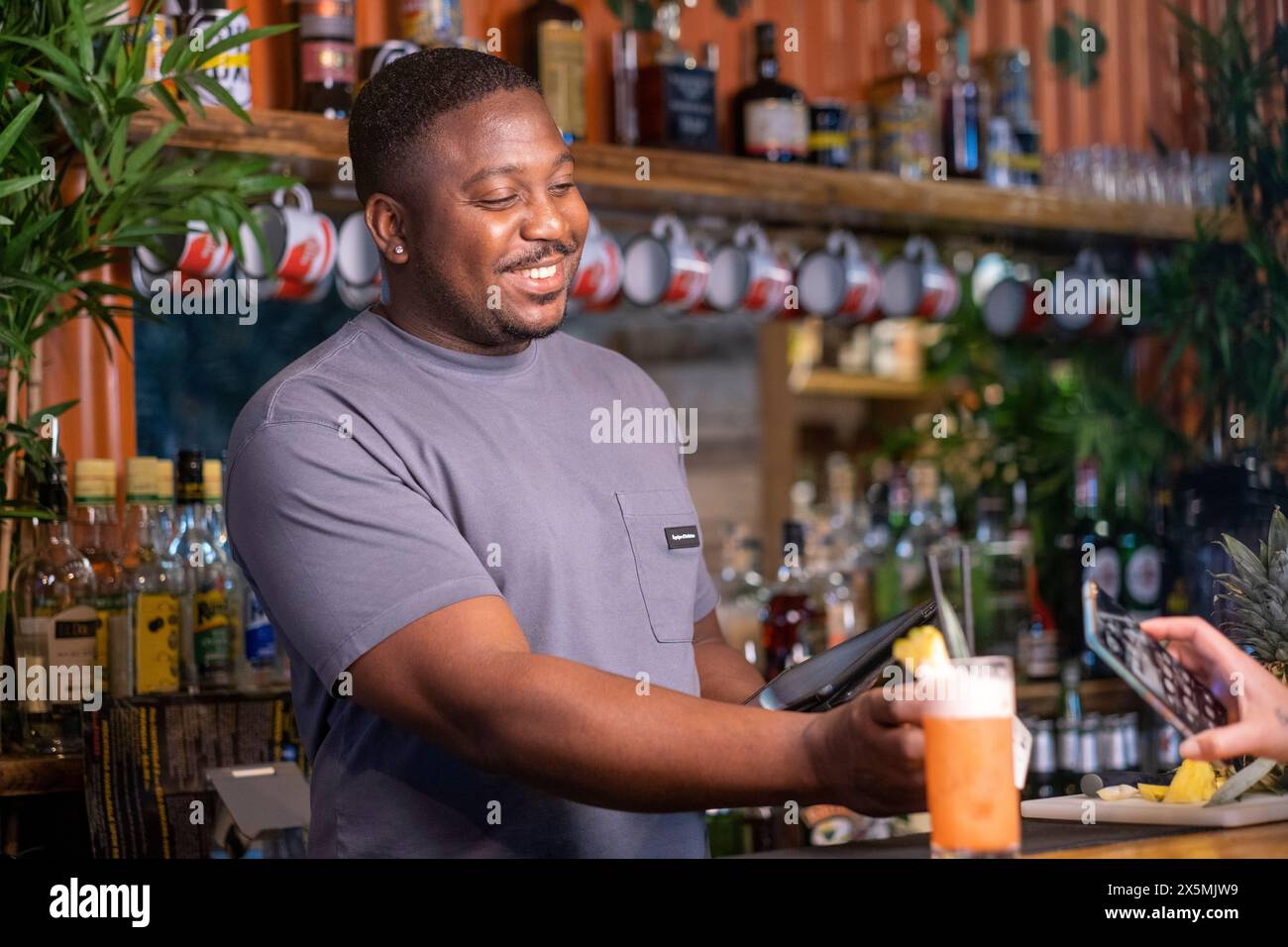 Barman souriant avec lecteur de voiture de crédit et tablette au bar, USUN wiek kobiety Banque D'Images