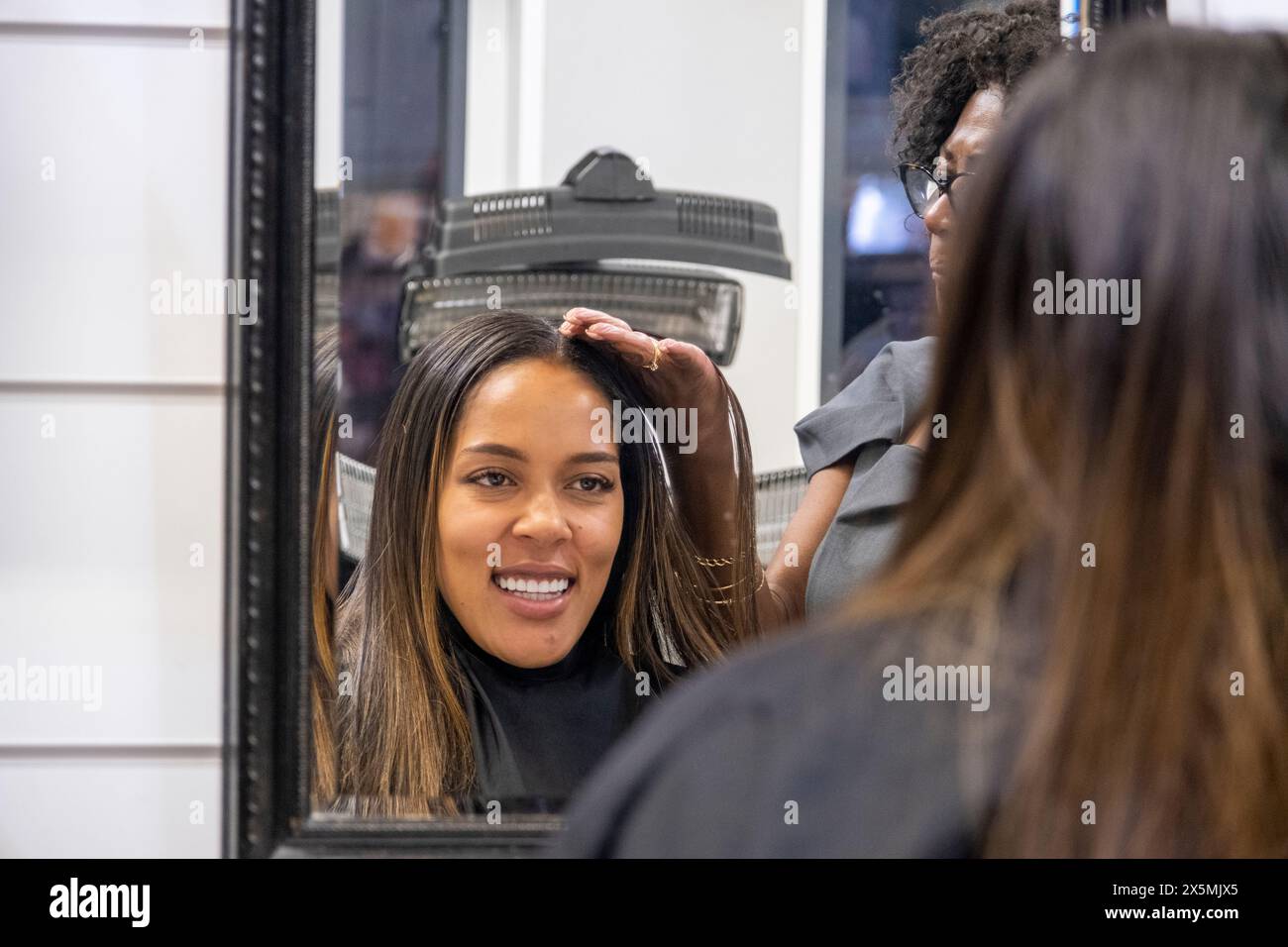 Client souriant et coiffeur reflété dans le miroir au salon de coiffure Banque D'Images