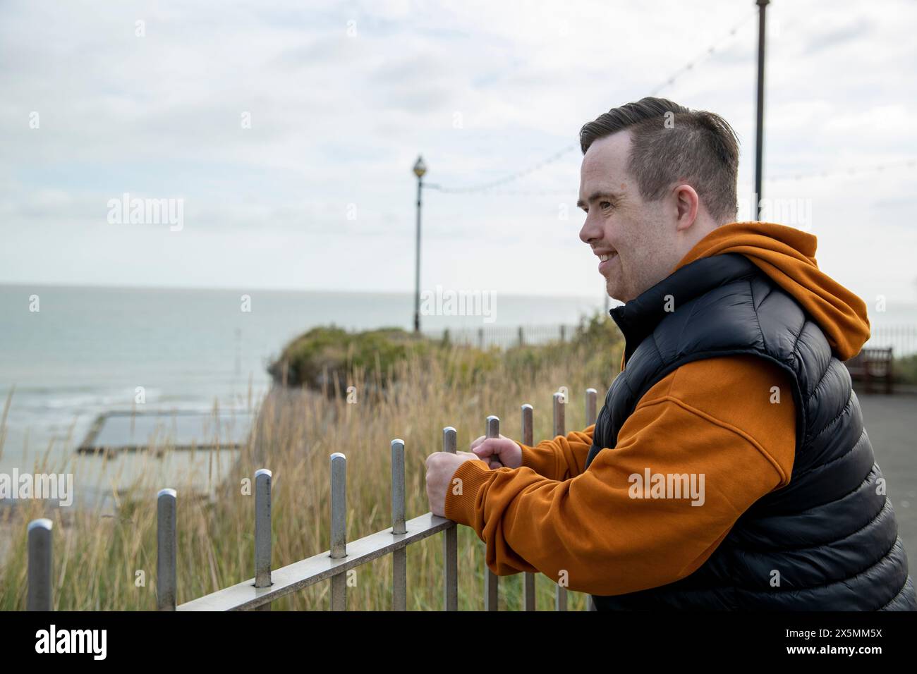 Homme penché sur la clôture regardant la côte de la mer Banque D'Images