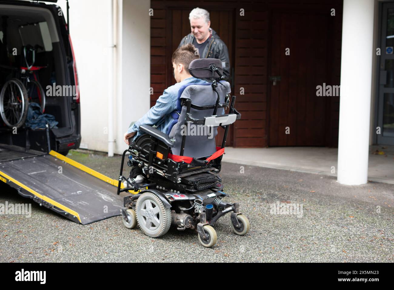 Père et fils handicapés utilisant un ascenseur pour fauteuil roulant Banque D'Images
