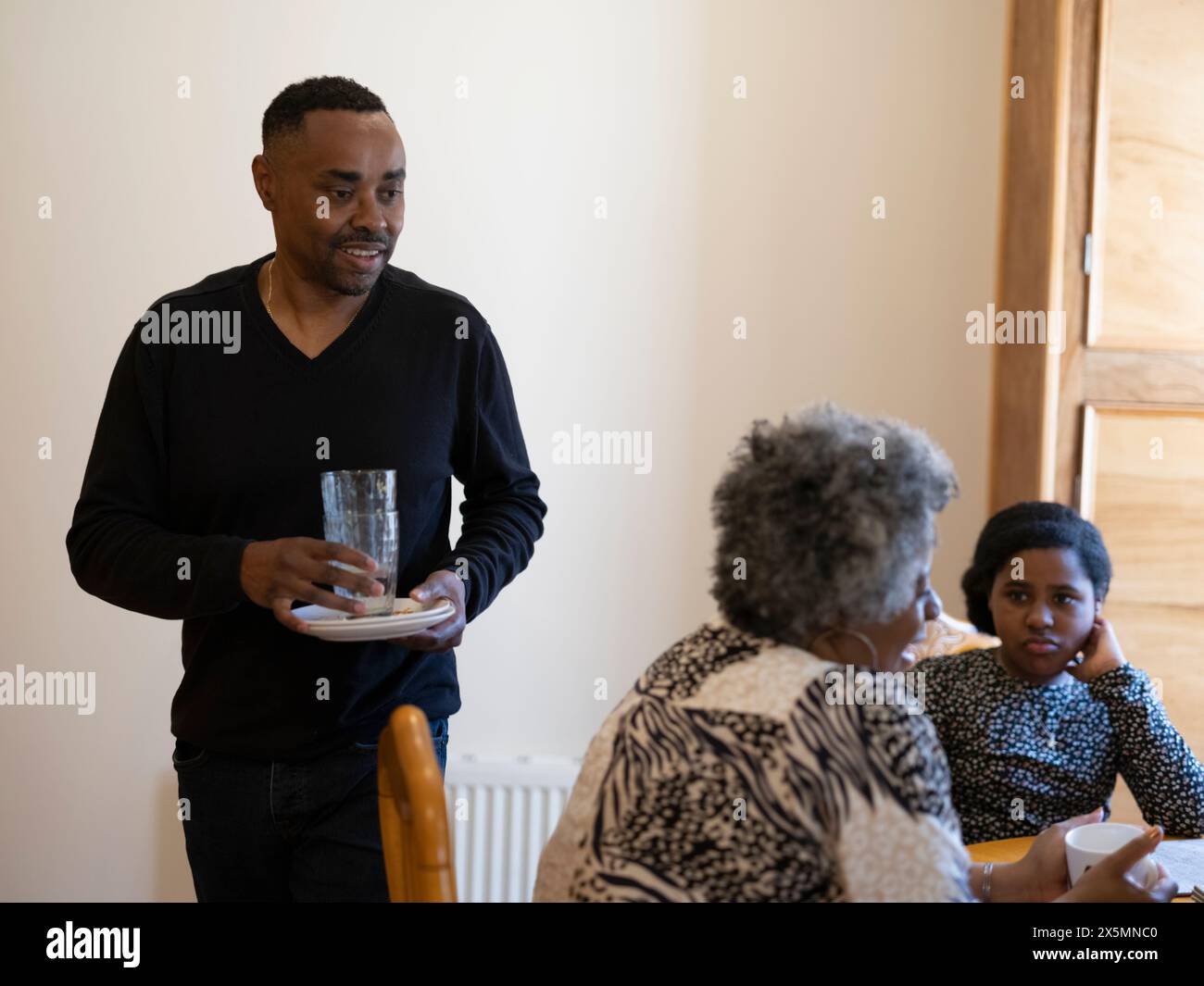 Père nettoyant après le petit déjeuner avec la famille Banque D'Images