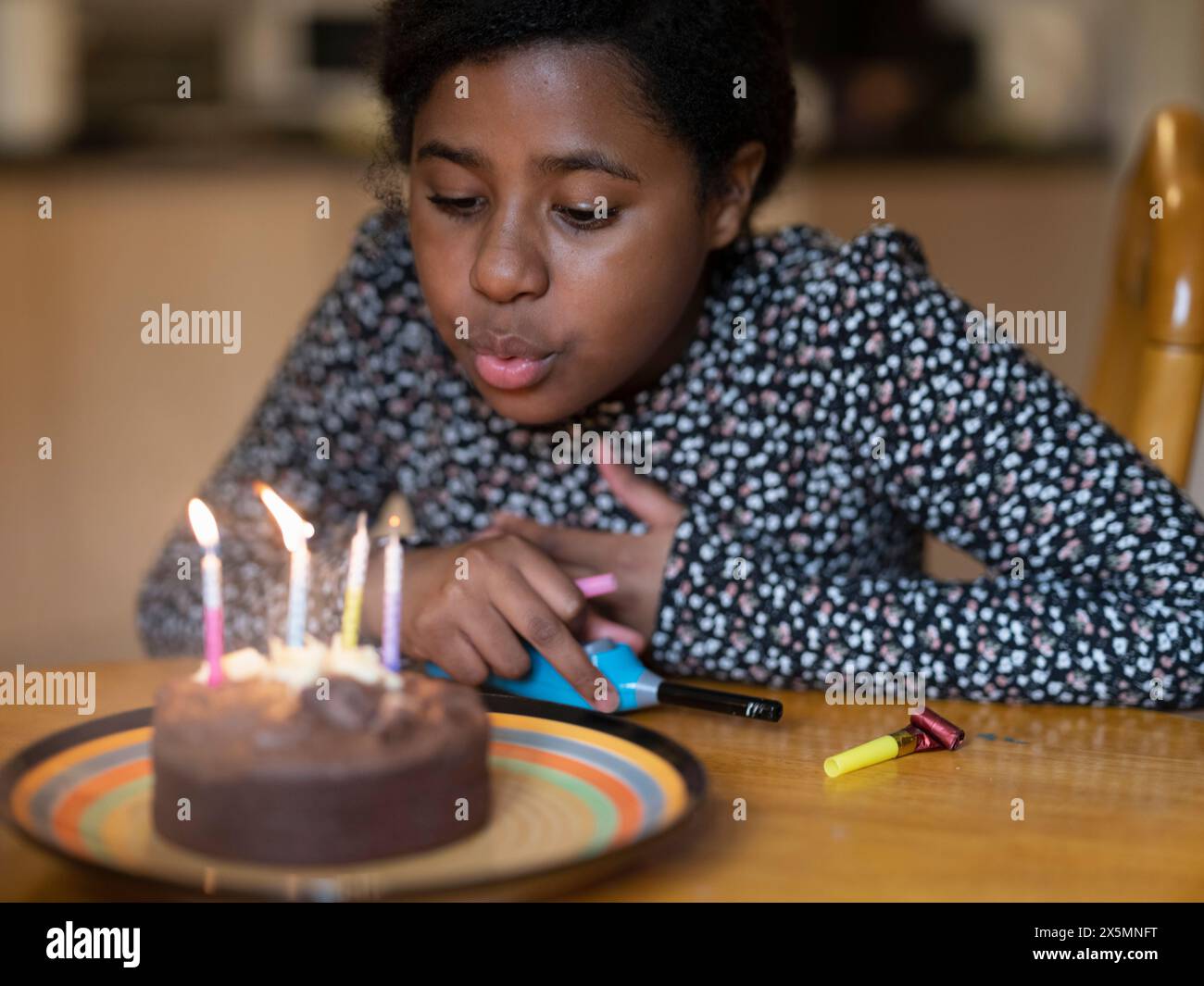 Girl blowing out candles on cake Banque D'Images