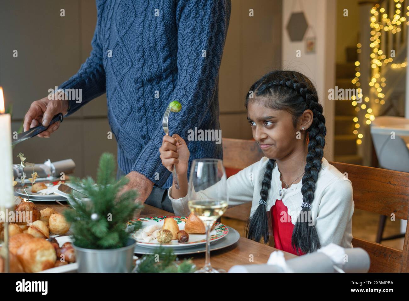 Fille mécontente avec chou de bruxelles sur la fourchette pendant le dîner de Noël Banque D'Images