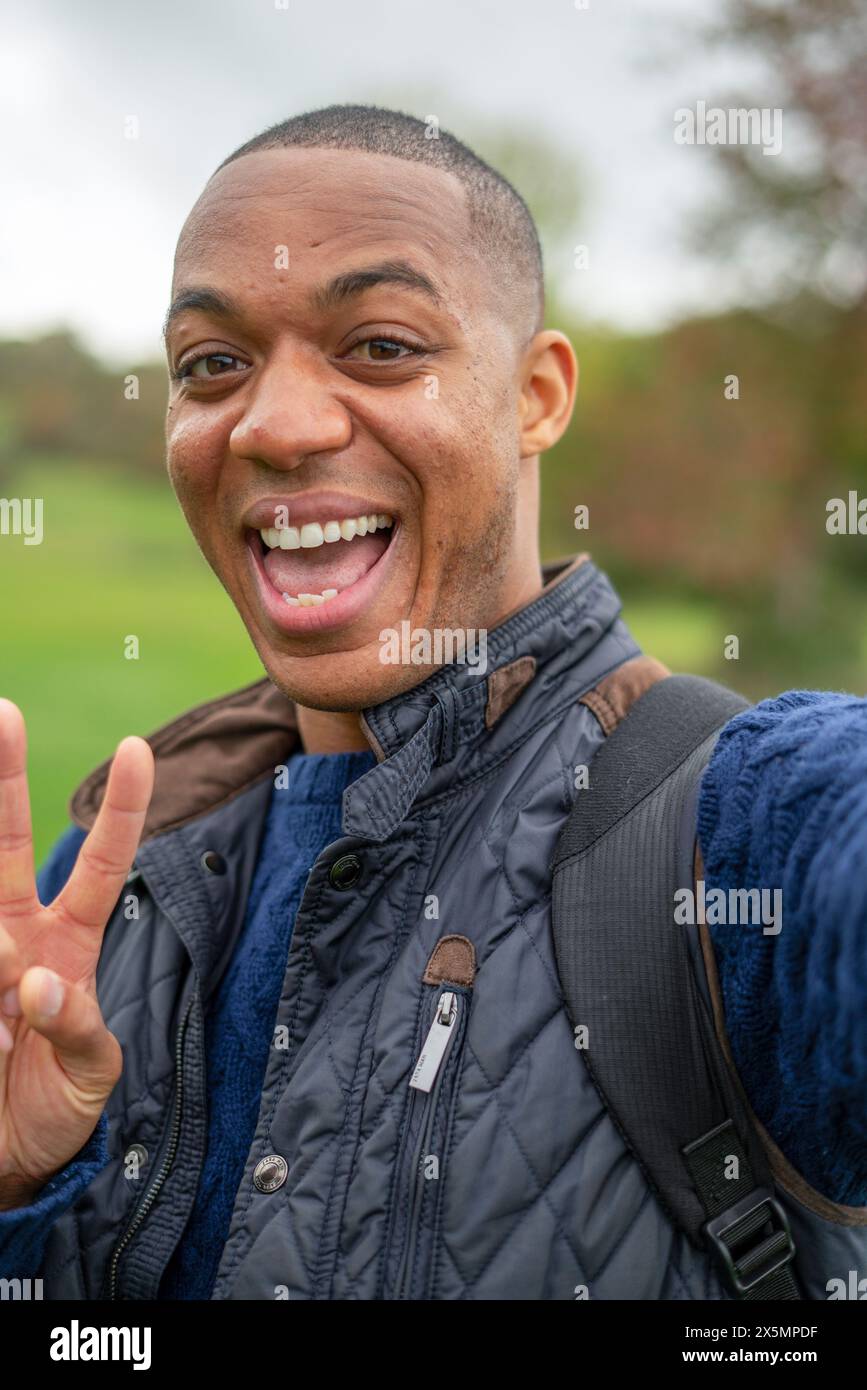 Portrait d'homme souriant montrant un geste de paix Banque D'Images