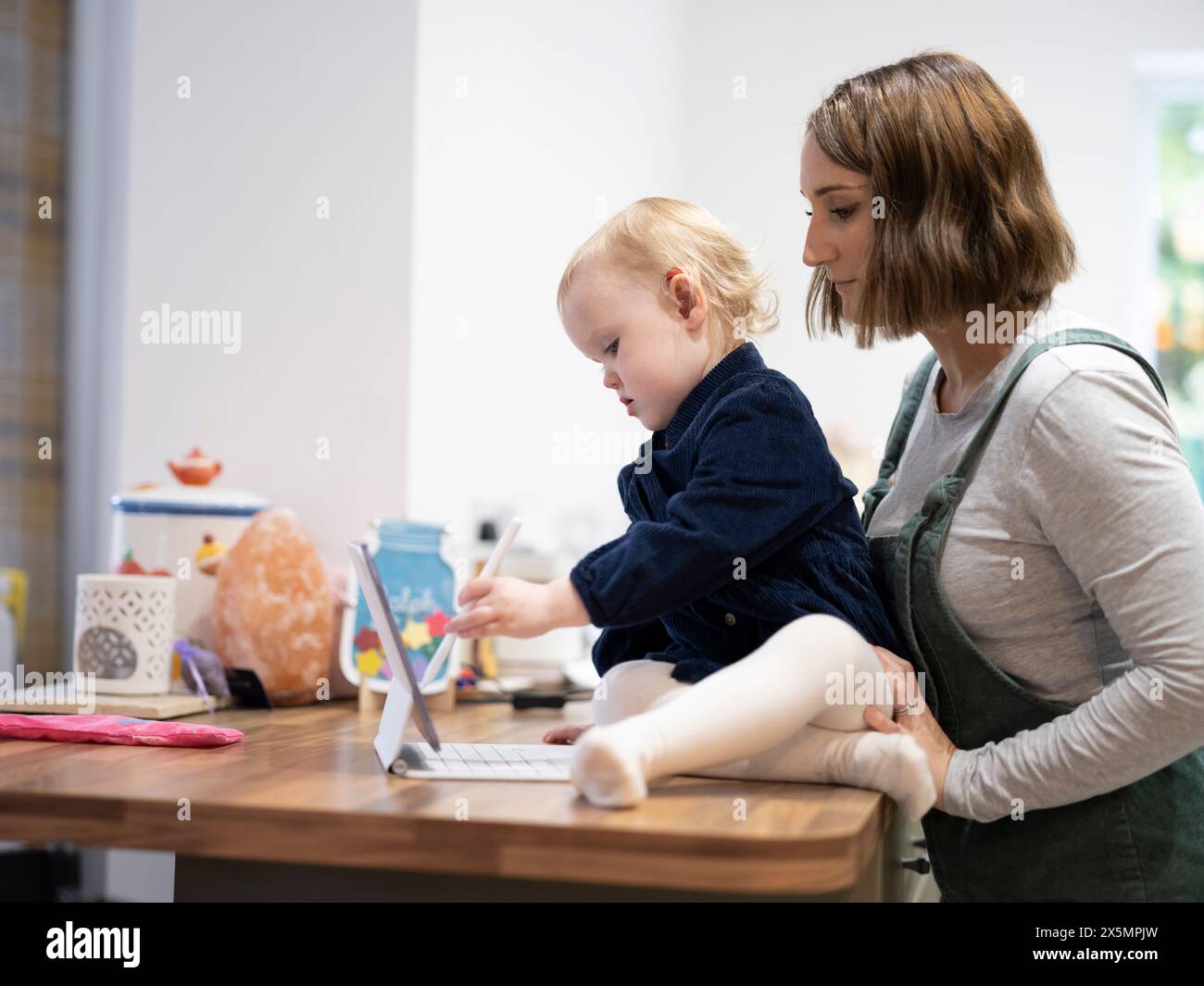 Mère debout à côté de sa fille à l'aide d'une tablette numérique Banque D'Images