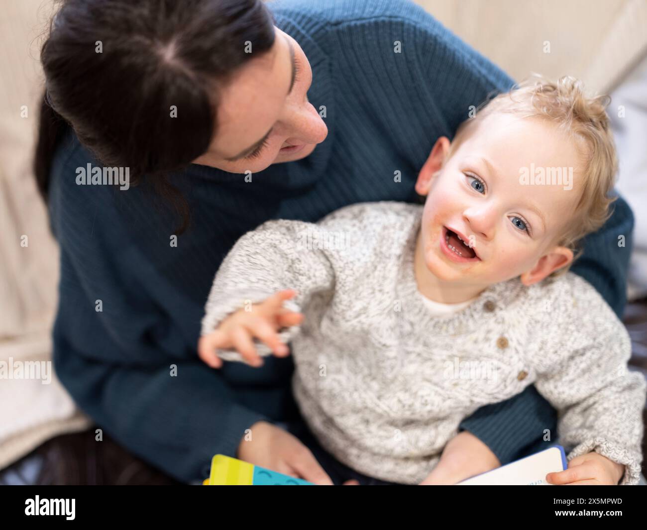 Garçon souriant avec paralysie cérébrale assis sur les genoux de la mère Banque D'Images