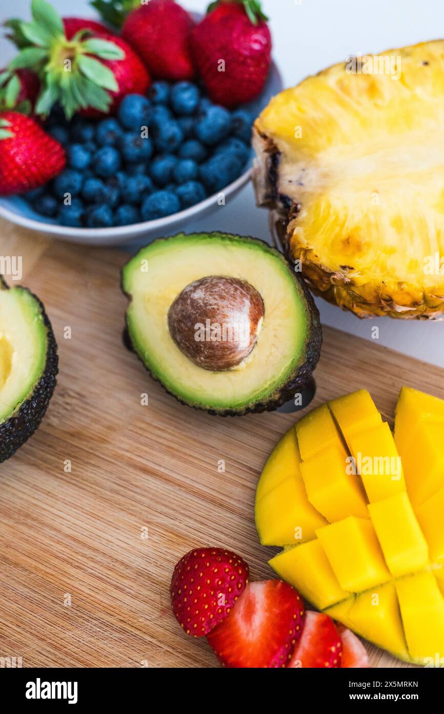 avocat, mangue, myrtilles, fraises sur une planche à découper dans la cuisine Banque D'Images