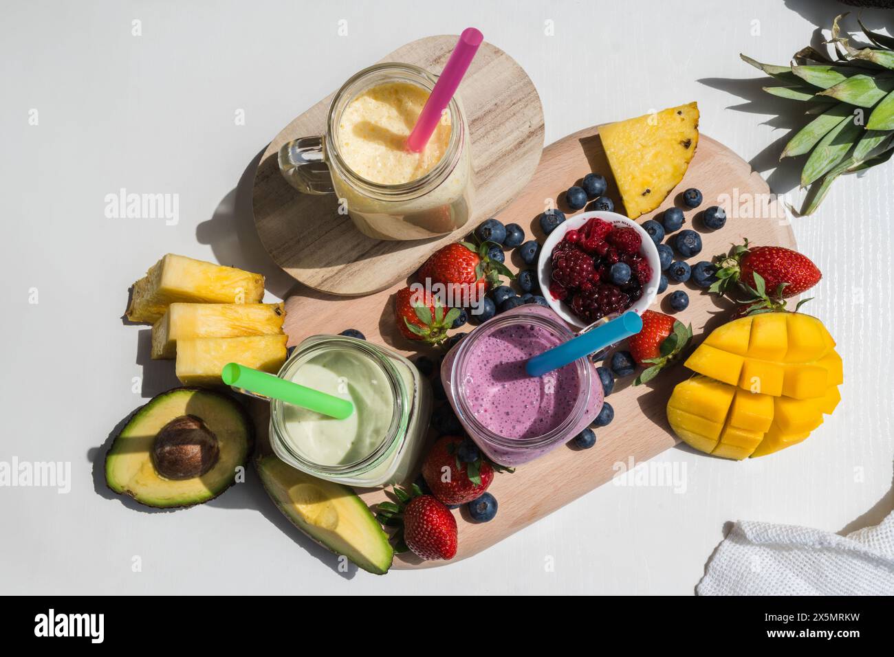 vue de dessus de smoothie coloré, régime de vitamines détox sain ou concept alimentaire végétalien, vitamines fraîches, boisson de petit déjeuner avec avocat, ananas, mangue, paille Banque D'Images