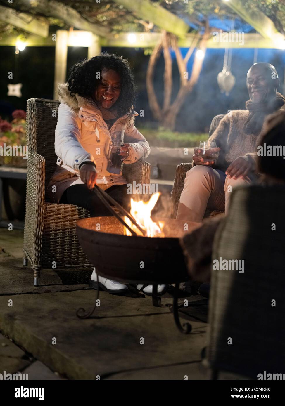 Homme et femme assis près de la fosse de feu sur le patio Banque D'Images