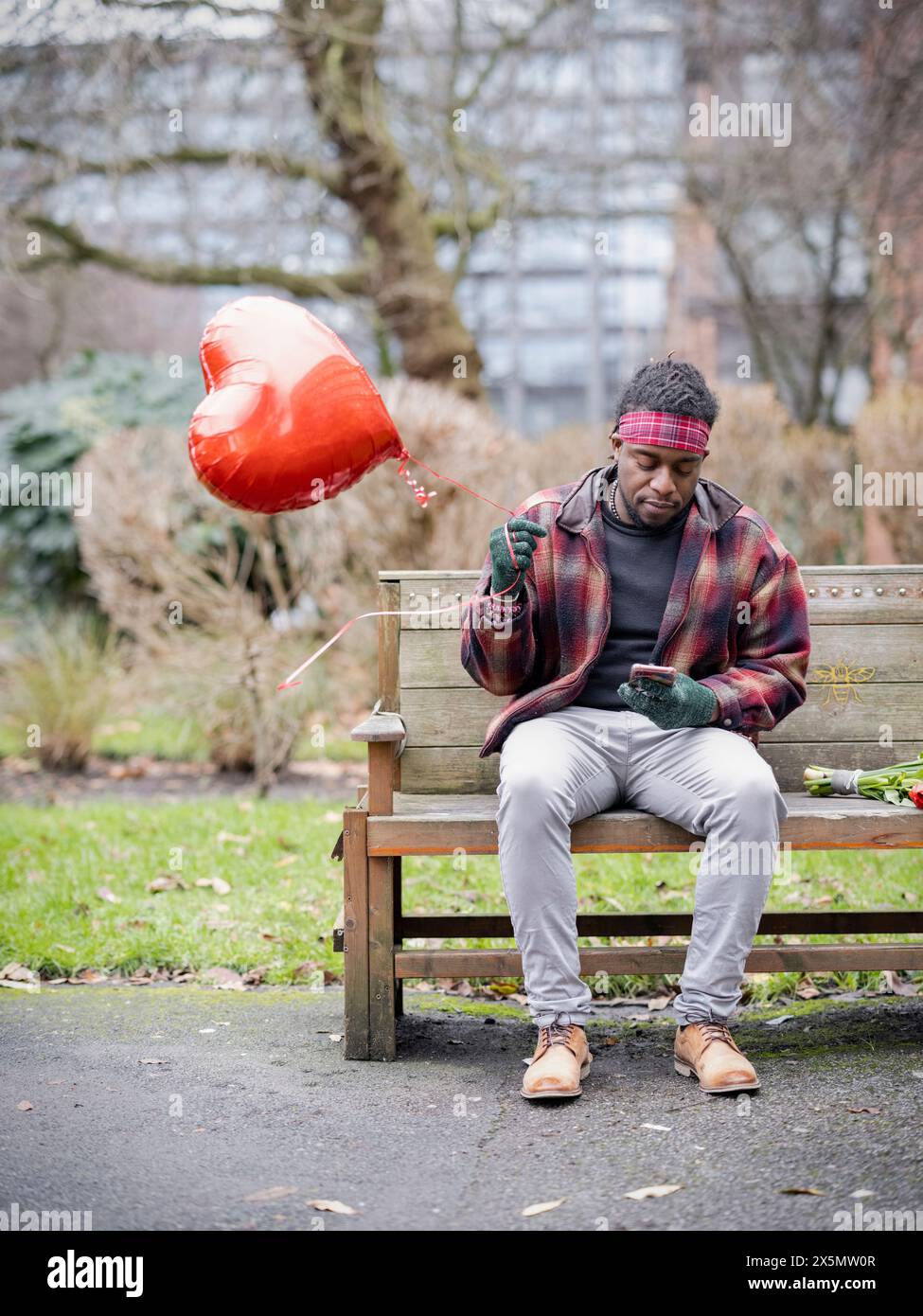 Homme avec ballon en forme de coeur assis sur le banc Banque D'Images