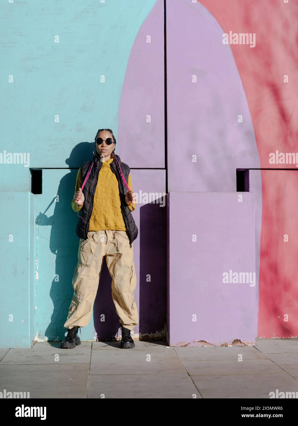 Portrait d'une jeune femme posant par un mur de graffitis coloré Banque D'Images