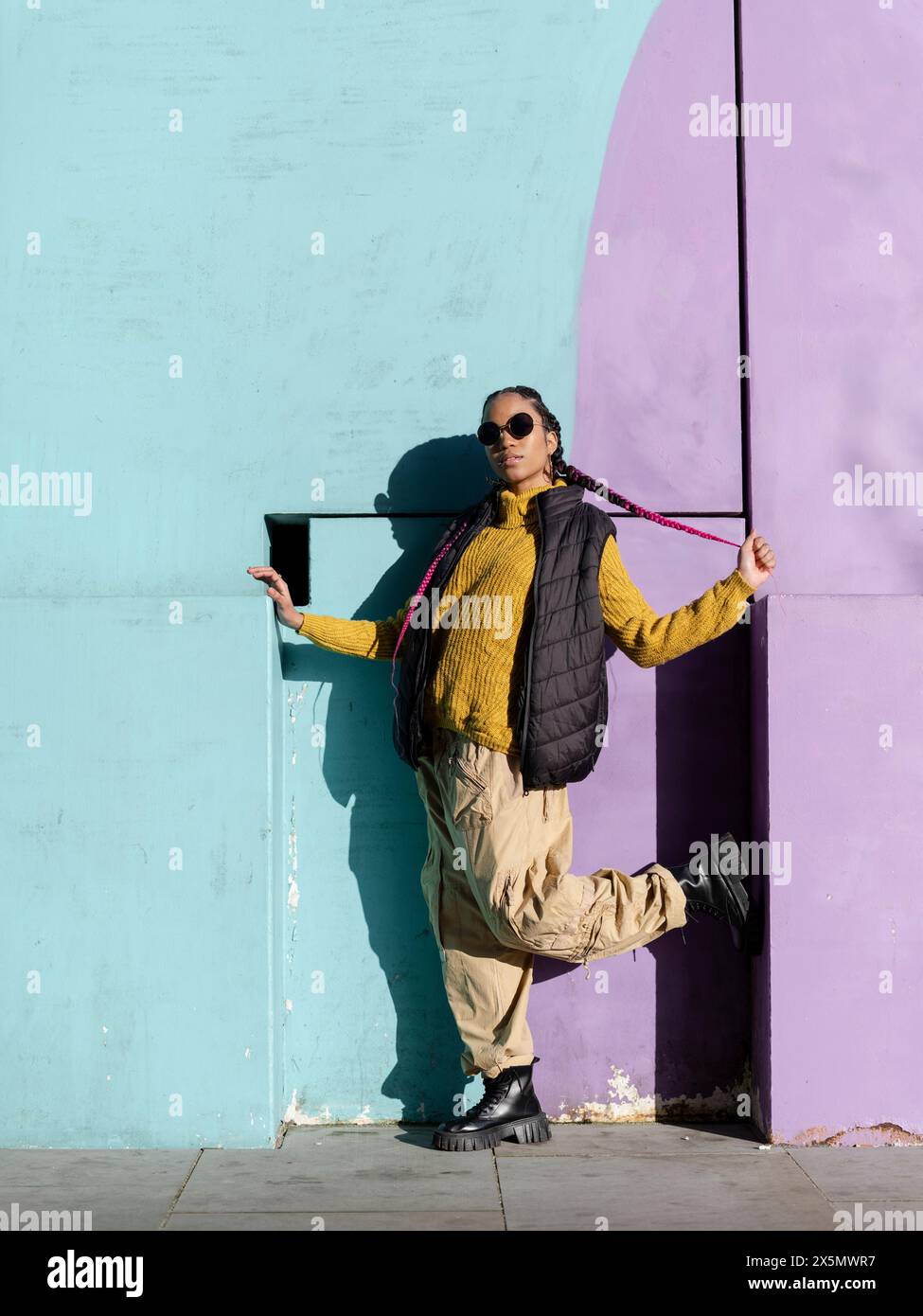 Portrait d'une jeune femme posant par un mur de graffitis coloré Banque D'Images