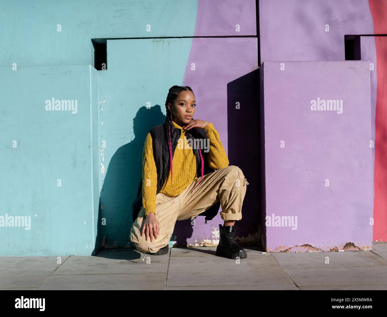 Portrait d'une jeune femme posant par un mur de graffitis coloré Banque D'Images