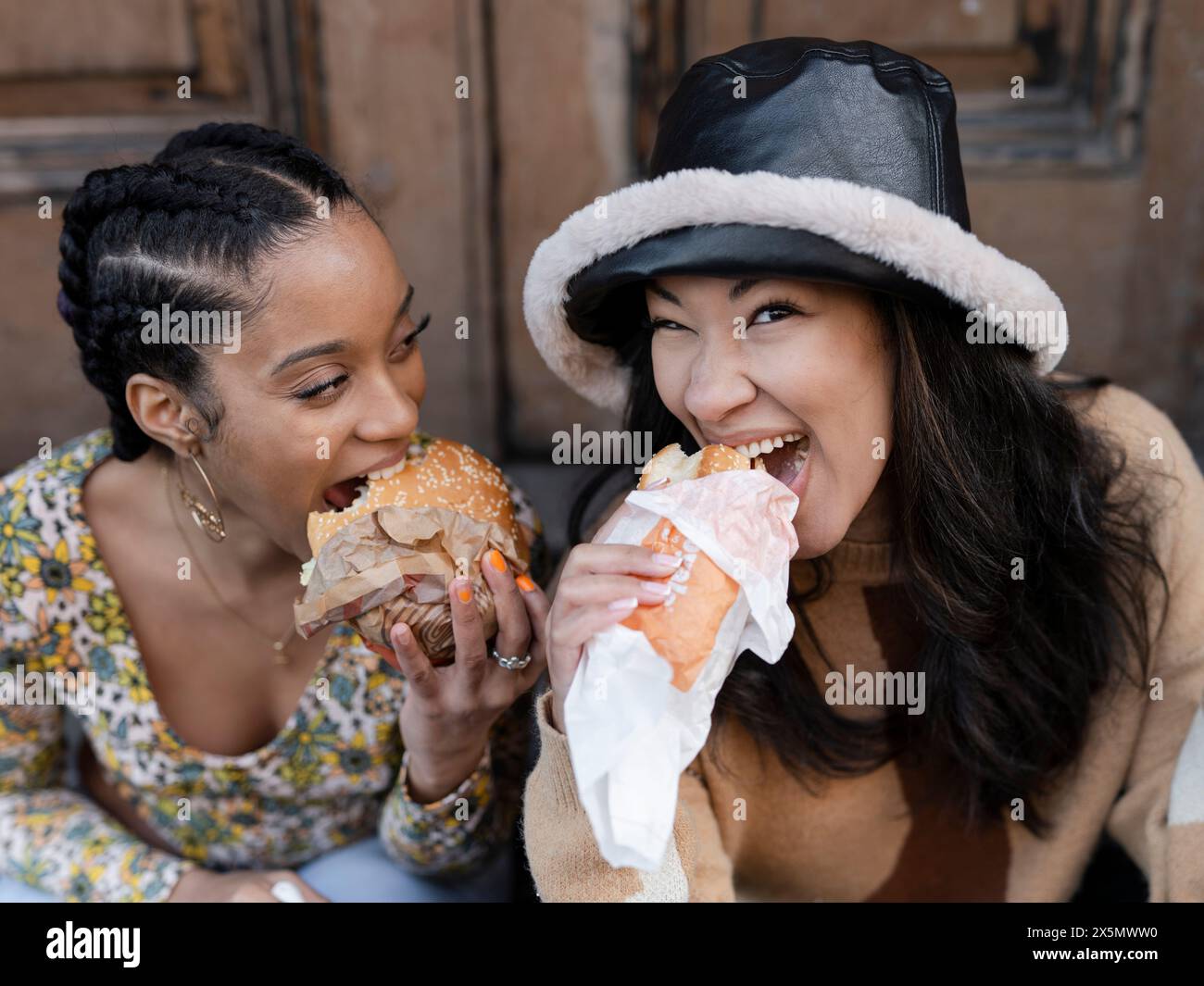 Deux jeunes femmes mangeant de la restauration rapide Banque D'Images