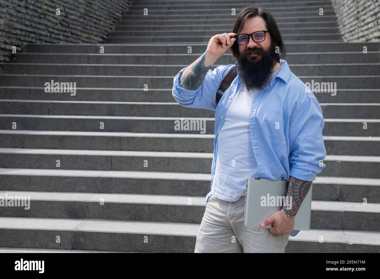 homme confiant dans des lunettes noires tenant un ordinateur portable. Gestionnaire souriant Banque D'Images