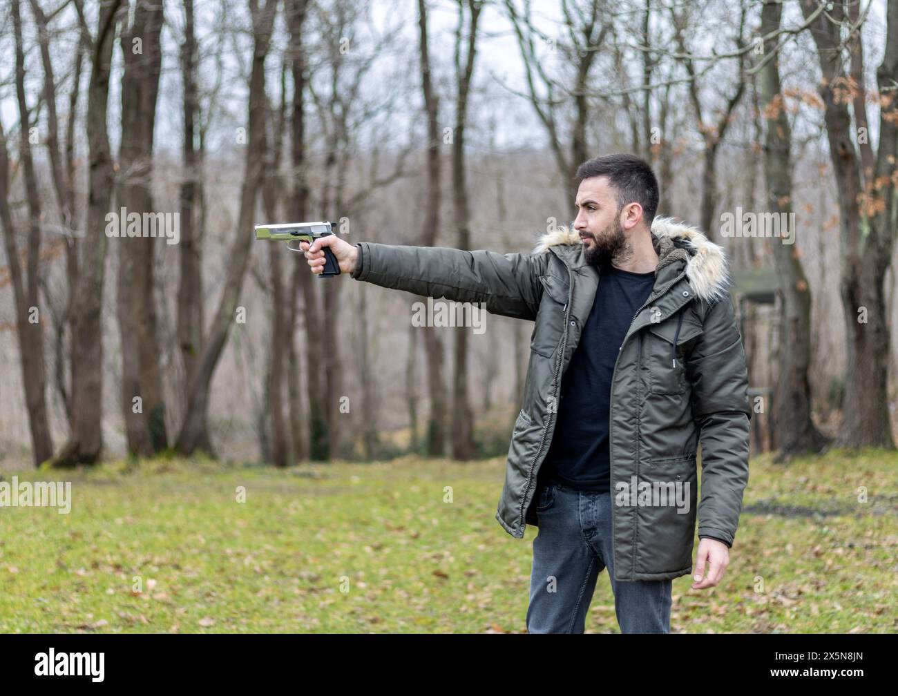 Le jeune homme vise et tire avec un pistolet dans la forêt Banque D'Images