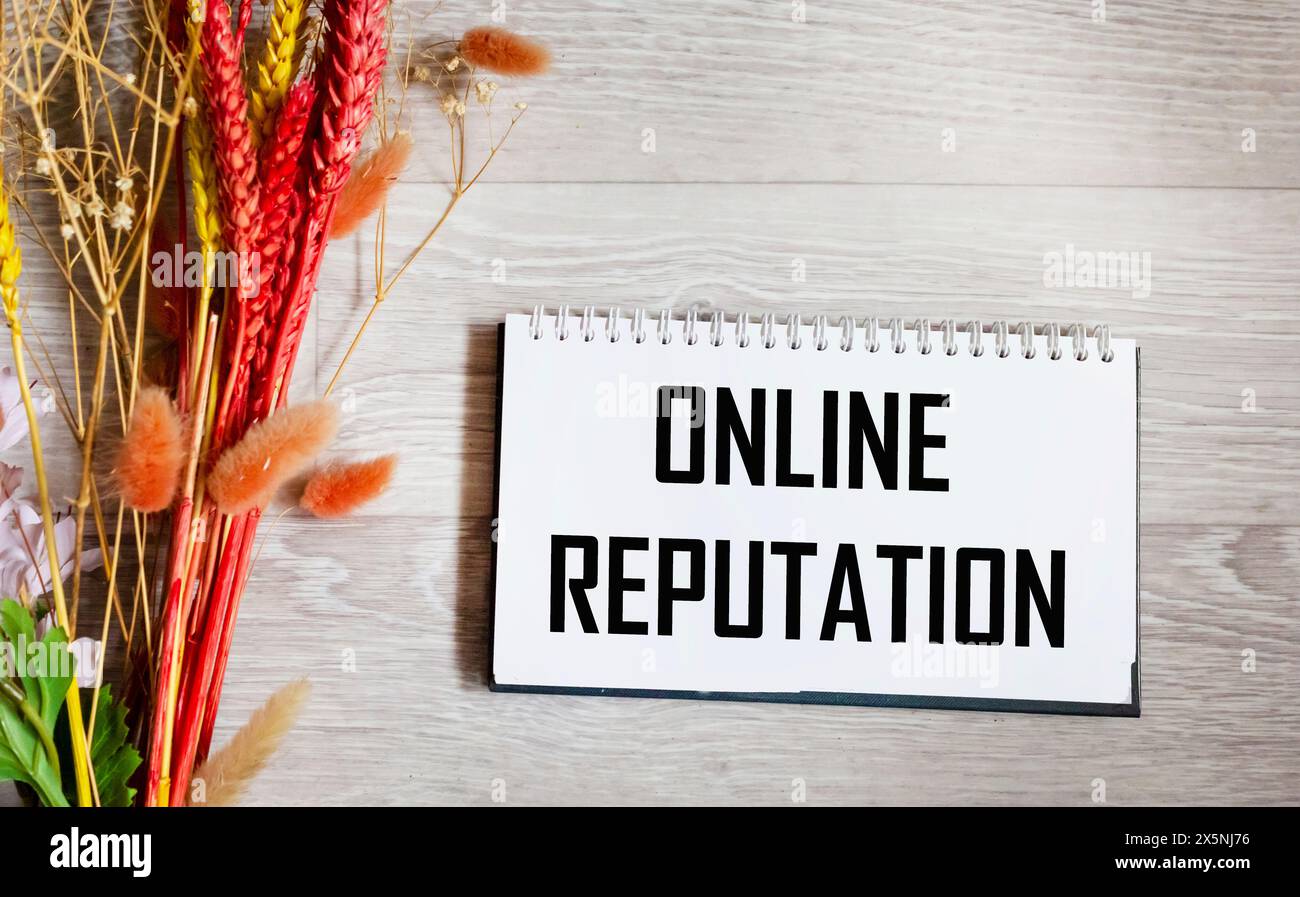 Bloc-notes avec le texte EN LIGNE RÉPUTATION fond gris avec un beau bouquet de fleurs séchées. Banque D'Images