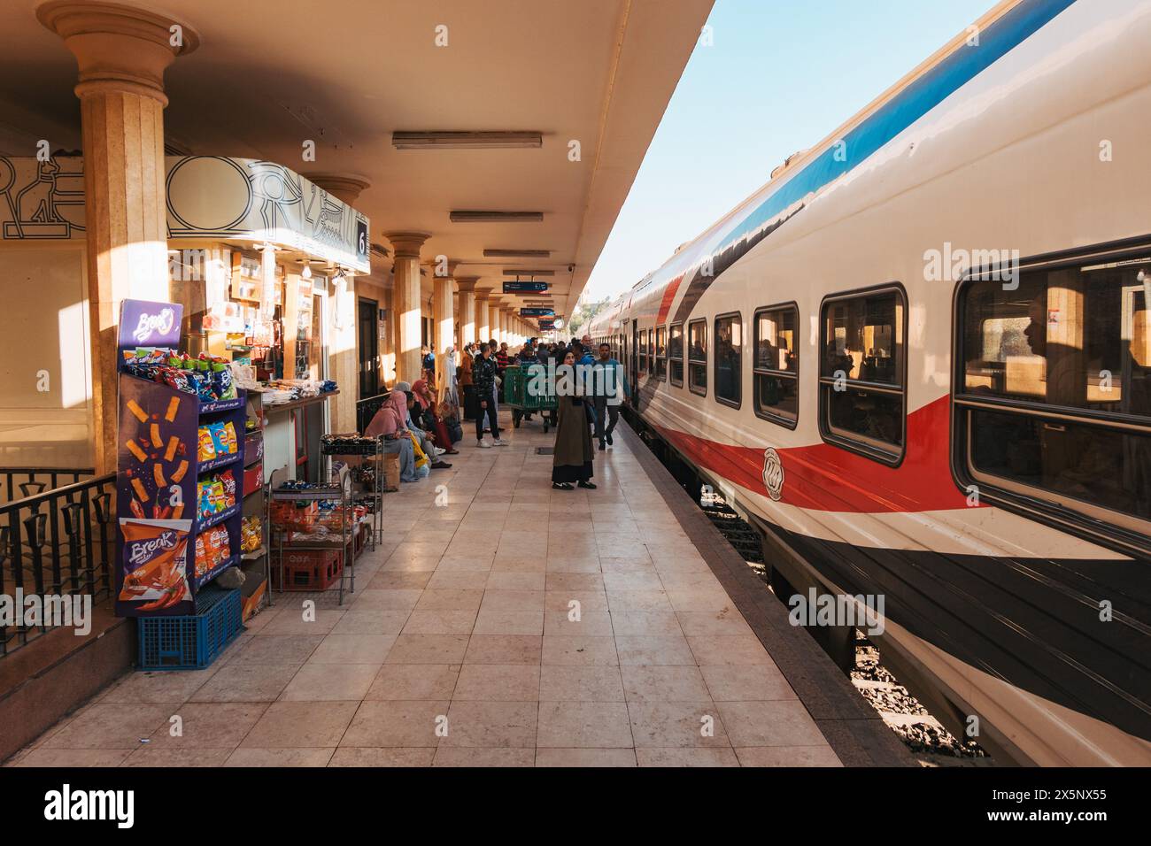 Les passagers attendent et les vendeurs vendent des collations alors qu'un train des chemins de fer égyptiens arrive à la gare de Louxor, en Égypte Banque D'Images