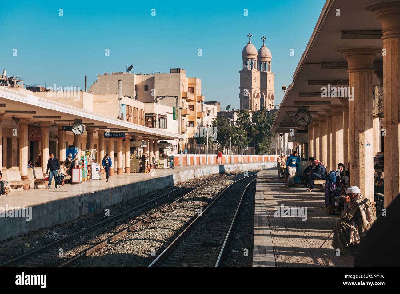 Les passagers attendent sur le quai de train à la gare de Luxor Railways en Égypte. L'église de l'ange Michael peut être vue en arrière-plan Banque D'Images