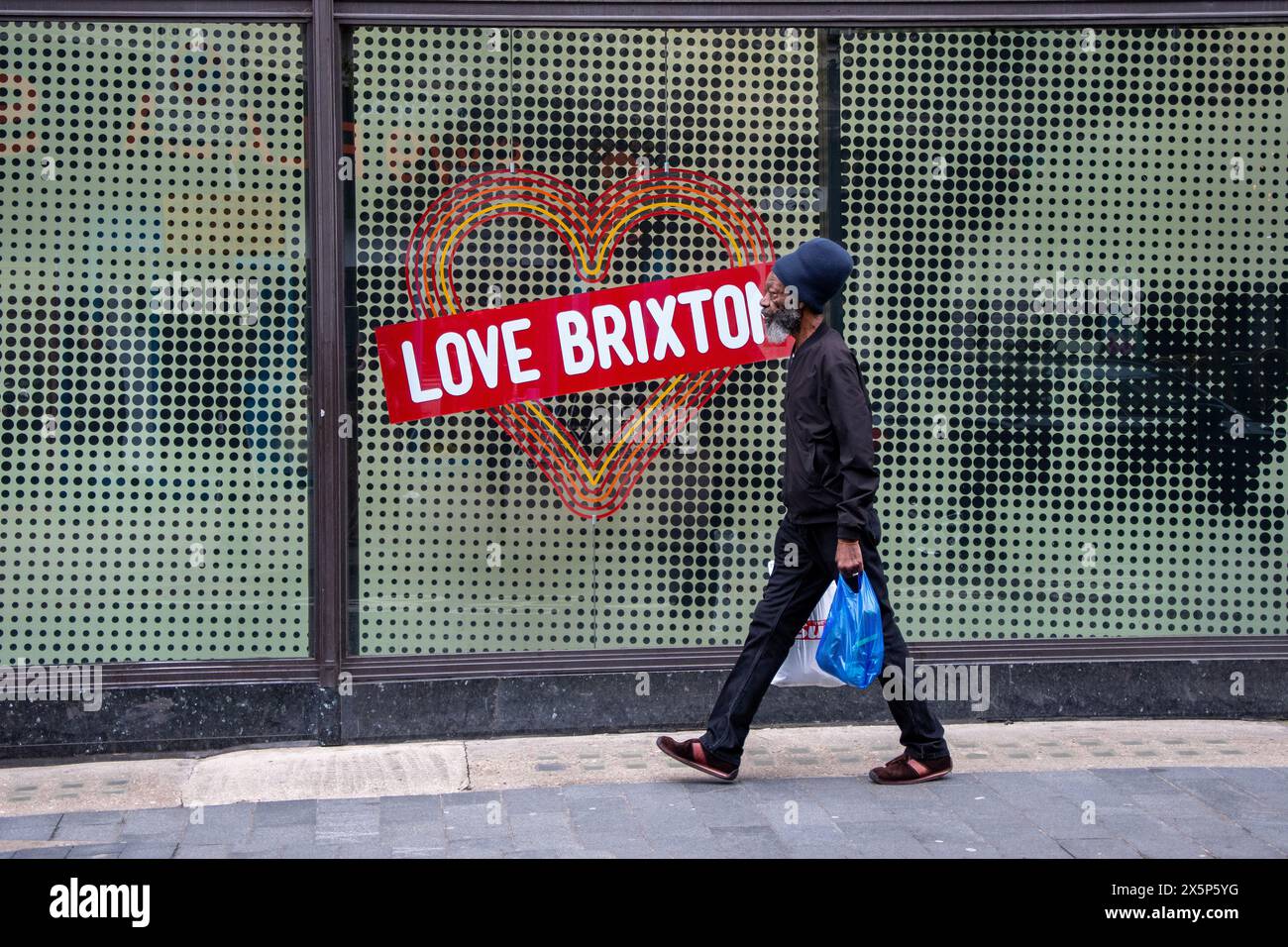 Photo de rue prise dans le sud de Londres d'un homme passant devant un autocollant dans une vitrine de magasin à Brixton Banque D'Images
