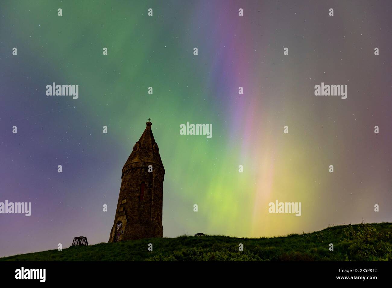 Les aurores boréales (ou aurores boréales) brillent derrière Hartshead Pike à Tameside, dans le Grand Manchester, en Angleterre, alors que l'une des tempêtes géomagnétiques les plus fortes depuis des années frappe la terre. Photo : Daniel Chesterton/phcimages.com crédit : PHC images LTD/Alamy Live News Banque D'Images