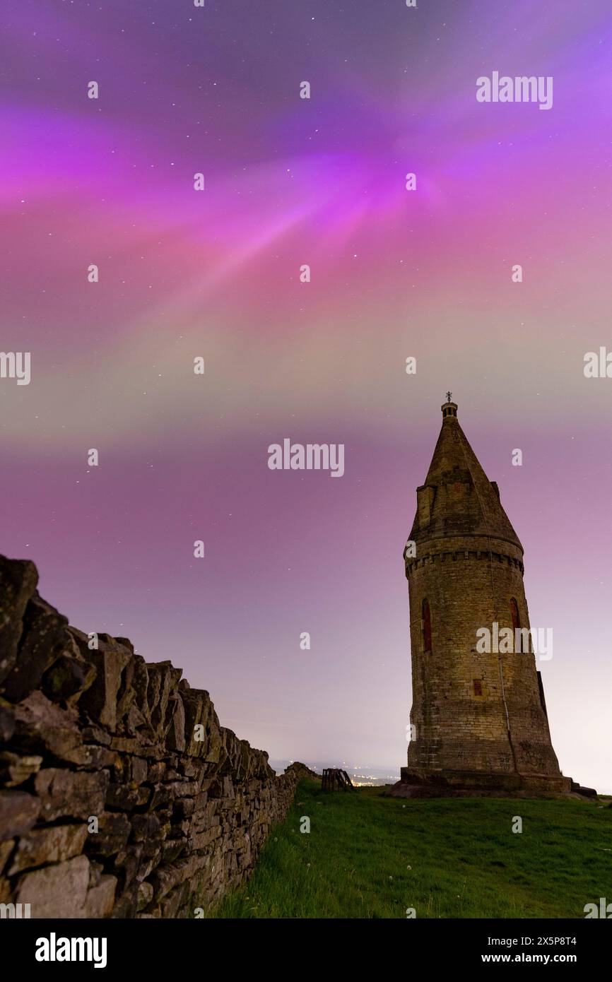 Les aurores boréales (ou aurores boréales) brillent derrière Hartshead Pike à Tameside, dans le Grand Manchester, en Angleterre, alors que l'une des tempêtes géomagnétiques les plus fortes depuis des années frappe la terre. Photo : Daniel Chesterton/phcimages.com crédit : PHC images LTD/Alamy Live News Banque D'Images