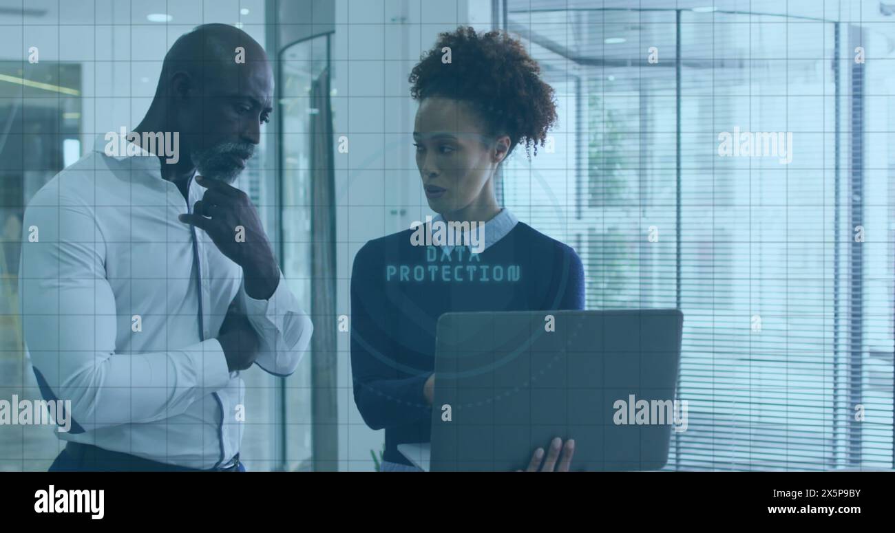 Cadre afro-américain et collègue biracial tenant un ordinateur portable, discutant du travail Banque D'Images