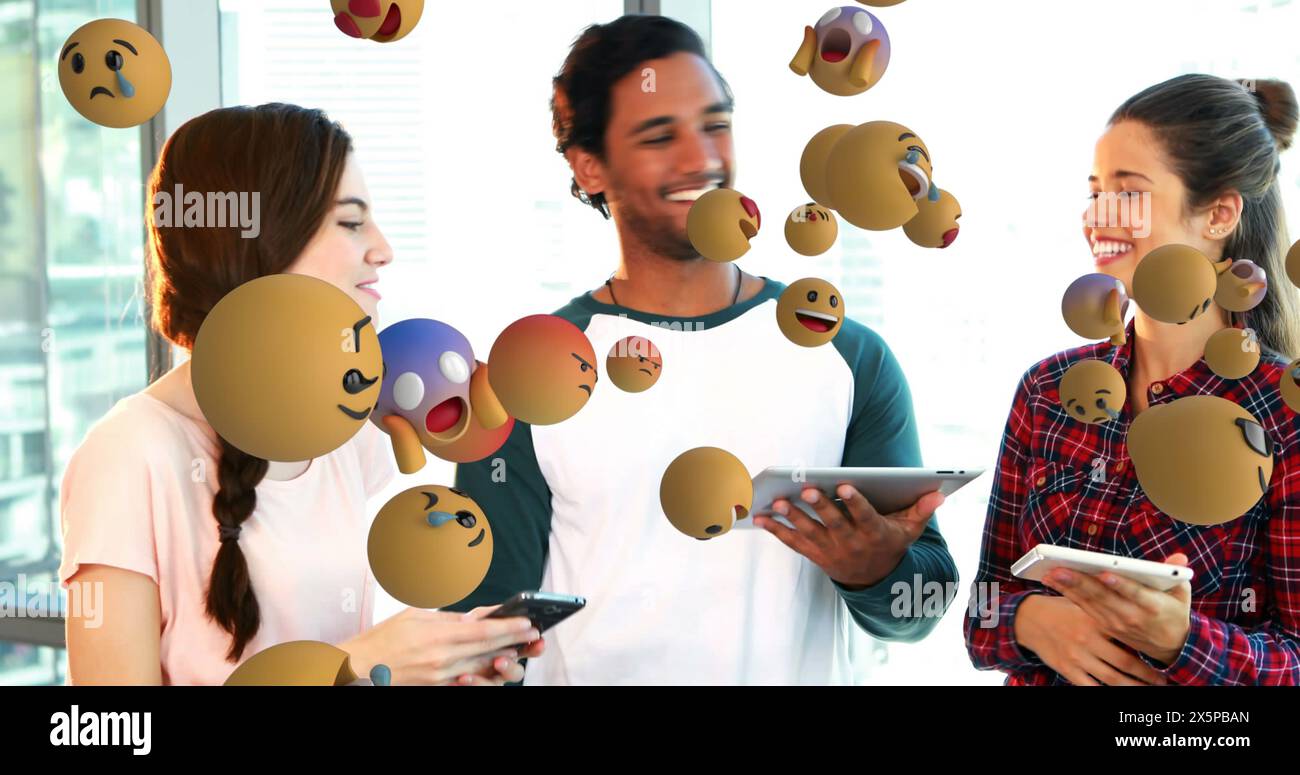 Deux femmes caucasiennes et un homme biracial, riant, partageant du contenu sur des appareils Banque D'Images