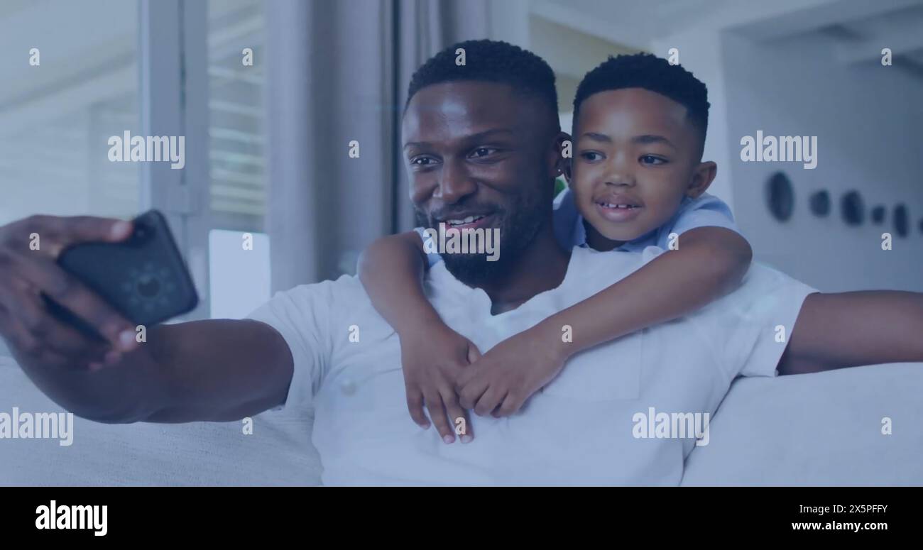 Père afro-américain et son fils aux cheveux noirs courts prennent un selfie sur un canapé Banque D'Images