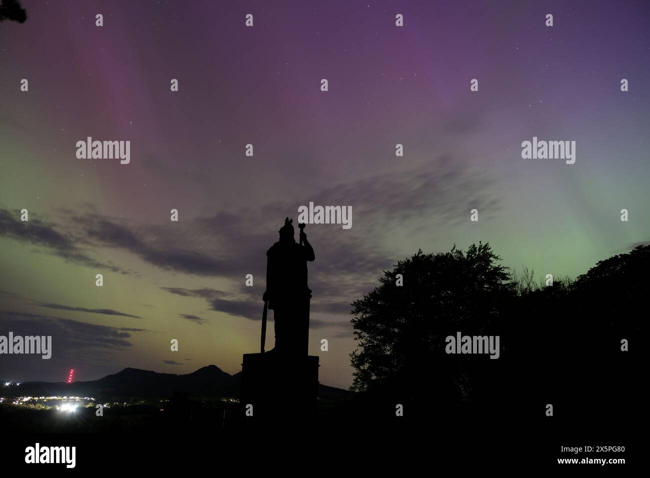 Melrose, Royaume-Uni. 11 mai 2024. La silhouette de la statue Wallace à Bemersyde regardant vers les Eiildons comme aurores boréales, peut être vue dans les frontières écossaises. Une forte tempête solaire dirigée vers la Terre a rendu les aurores boréales visibles dans les Scottish Borders. Les experts en météorologie spatiale avaient émis un rare avertissement de tempête géomagnétique grave (G4) pour ce week-end, le premier en près de 20 ans. La tempête, causée par de puissantes éruptions connues sous le nom d'éjections de masse coronale, peut déclencher des affichages spectaculaires d'aurora image Credit : Rob Gray/Alamy Live News Banque D'Images